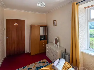 a bedroom with a bed and a dresser and a window at Kilpatrick Farm House in Pinmore