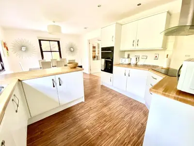 a kitchen with white cabinets and wooden floors at Lochindaal - Beautiful, Spacious 4 Bedroom House in Kintyre in Whitehouse