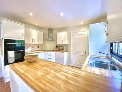 a kitchen with white cabinets and a wooden counter top at Lochindaal - Beautiful, Spacious 4 Bedroom House in Kintyre in Whitehouse