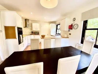 a kitchen with a black table and white chairs at Lochindaal - Beautiful, Spacious 4 Bedroom House in Kintyre in Whitehouse