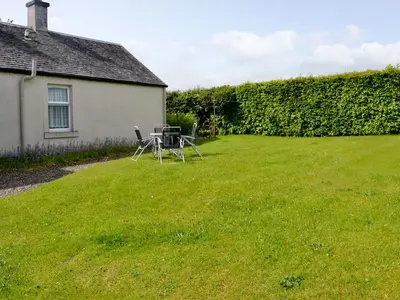 a table and chairs in a yard next to a house at Blairhosh Cottage in Balloch