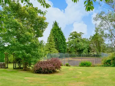 a park with a fence and trees and a tennis court at Blairhosh Cottage in Balloch