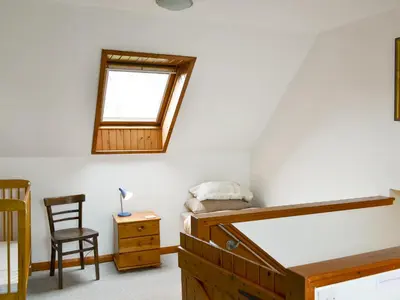 a bedroom with a bed and a window and a chair at Blairhosh Cottage in Balloch
