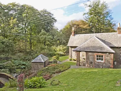 an old stone house with a garden in front of it at Gardener's Cottage-Uxt in Corsock