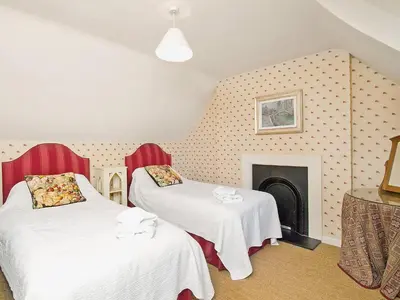 two beds in a room with a fireplace at Gardener's Cottage-Uxt in Corsock