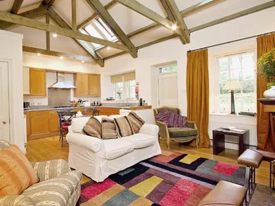 a living room with a white couch and a kitchen at Stables Cottage-Uud in Corsock