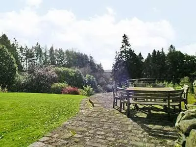 a bench sitting on a stone path in a park at Marwhin House - Swwr in Kirkpatrick Durham