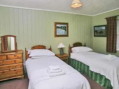 a bedroom with two beds and a dresser and a mirror at Marwhin Cottage - Swws in Kirkpatrick Durham