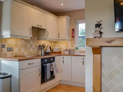 a kitchen with white cabinets and a sink at Swallow Lodge in Carsphairn