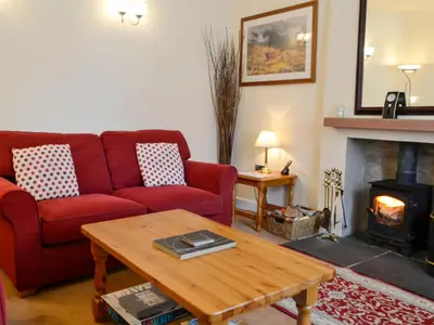 a living room with a red couch and a fireplace at Kirsty Cottage in Moffat