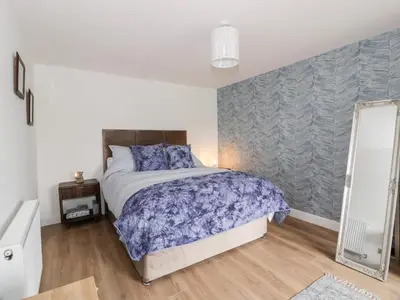 a bedroom with a bed and a mirror in it at Braeface Cottage in Bonnybridge