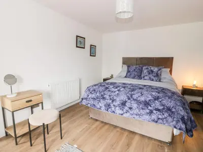 a bedroom with a bed and a table and a stool at Braeface Cottage in Bonnybridge