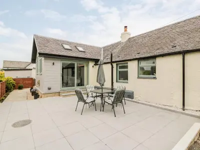 a patio with a table and chairs and a house at Braeface Cottage in Bonnybridge
