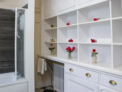 a bathroom with white shelves and flowers in vases at Rob Roy Apartment in Stirling