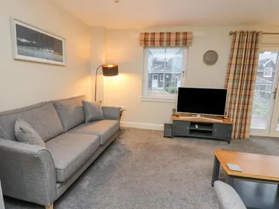 a living room with a couch and a flat screen tv at Taigh Geal in Killin