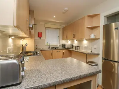 a kitchen with wooden cabinets and a stainless steel refrigerator at Taigh Geal in Killin