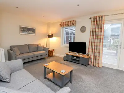 a living room with a couch and a flat screen tv at Taigh Geal in Killin