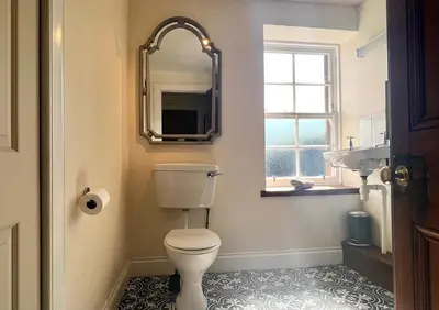 a bathroom with a toilet and a mirror and a window at Eckford House in Dunoon