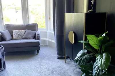 a living room with a blue couch and a plant at Stunning 3 bedroom Victorian home near Pollok country park in Glasgow