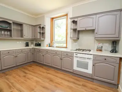 a large kitchen with white cabinets and a window at Mars Hill Upper in Dunoon