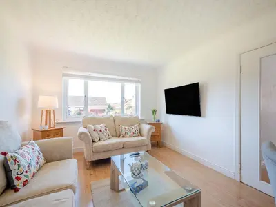 a living room with a couch and a tv at Seamill Cottage in Seamill