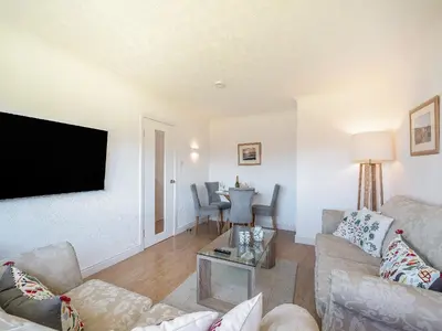a living room with a couch and a flat screen tv at Seamill Cottage in Seamill