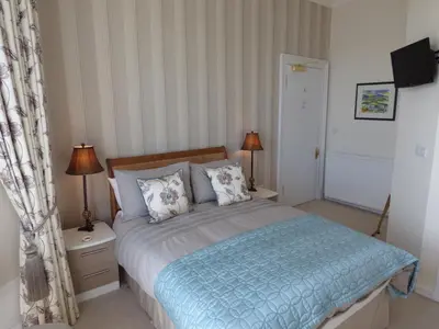 a bedroom with a bed with a blue comforter and two lamps at Douglas Park Guest House in Dunoon