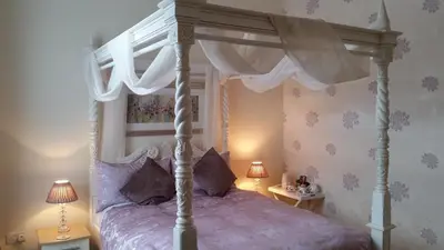 a bedroom with a canopy bed and two lamps at Douglas Park Guest House in Dunoon