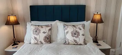 a bed with a green headboard and two lamps at Douglas Park Guest House in Dunoon