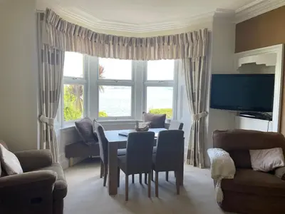 a living room with a table and chairs and a tv at Bayside - Breathtaking views of the Clyde in Rothesay
