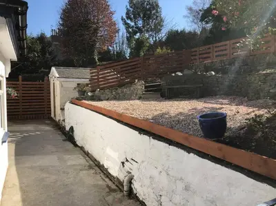 a garden with a retaining wall and a fence at The Villas in Helensburgh