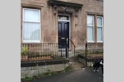 a dog standing in front of a house at Snug - Fountain Bank Apartment in Helensburgh