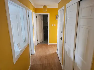 a hallway with yellow walls and white doors at Snug - Colquhoun Square Apartment in Helensburgh