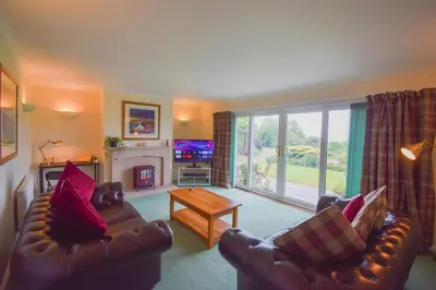 a living room with two couches and a fireplace at Heatherbank Cottage in Onich