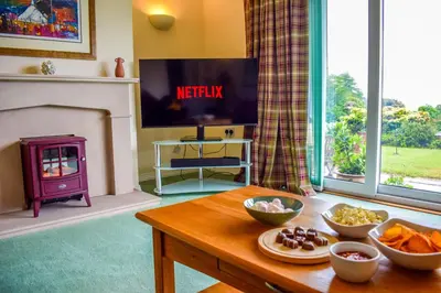 a living room with a tv and a table with food at Heatherbank Cottage in Onich
