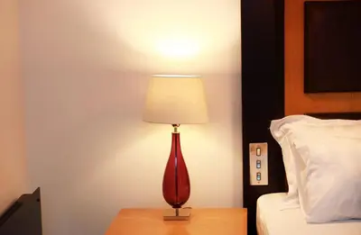 a red lamp sitting on a table next to a bed at Maltings Hotel in Dunfermline