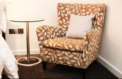 a chair with a pillow sitting next to a table at Maltings Hotel in Dunfermline