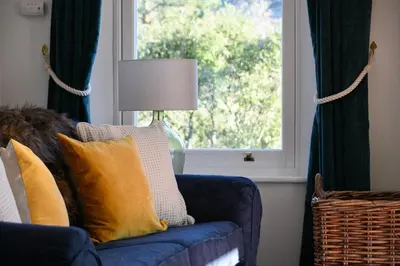 a blue couch in a living room with a window at Achalic Farm House in Lerags