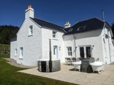 a white house with a bath tub and a sink at Achalic Farm House in Lerags