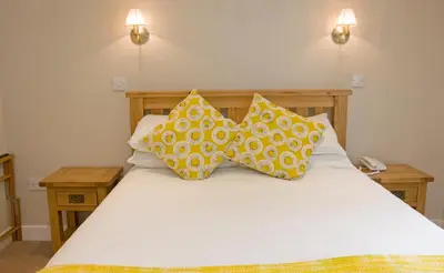 a bed with yellow and white pillows on it at Falls of Lora Hotel in Oban