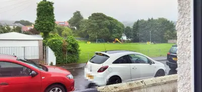 two cars parked in a parking lot with a park at Parkside 2 bedrooms appartment with encolsed garden in Largs