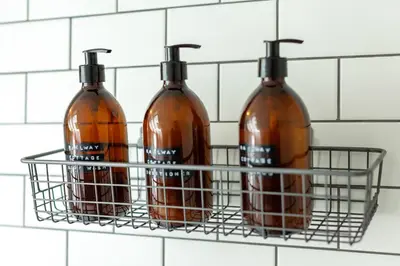 four bottles in a basket on a bathroom wall at Railway Cottage in Killin