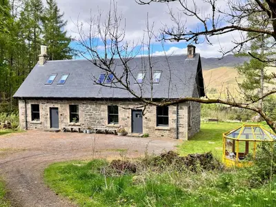 an old stone house in the middle of a field at Railway Cottage in Killin