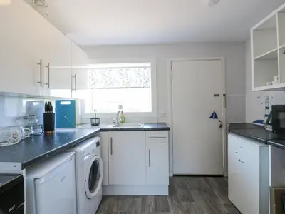 a kitchen with white cabinets and a washer and dryer at 22 Turnberry Road in Girvan