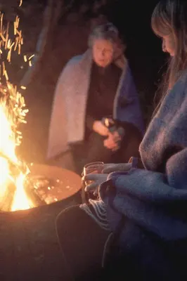 a woman looking at her cell phone next to a fire at Eastside Steading - Family barn in the Pentland Hills, Edinburgh in Penicuik