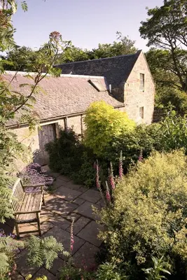 a garden with a bench in front of a building at Eastside Byre - Family cottage in the Pentland Hills near Edinburgh in Penicuik