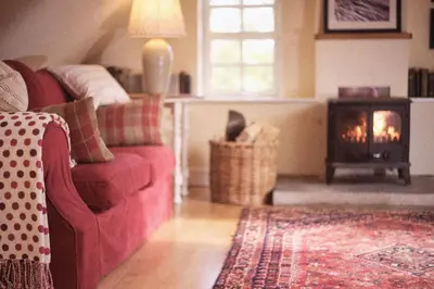 a living room with a red couch and a fireplace at Eastside Byre - Family cottage in the Pentland Hills near Edinburgh in Penicuik
