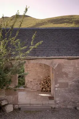 a brick building with a pile of fire wood at Eastside Byre - Family cottage in the Pentland Hills near Edinburgh in Penicuik