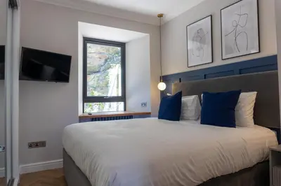 a bedroom with a large white bed with blue pillows at Oban Apartments in Oban