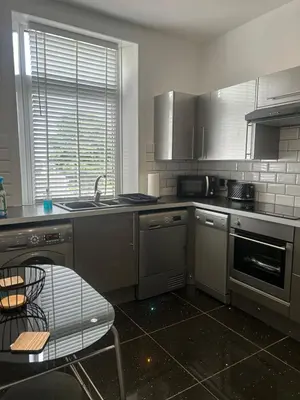 a kitchen with stainless steel appliances and a table at 1L Albert Place Maddiston Road Brightons Falkirk FK2 0JX in Polmont